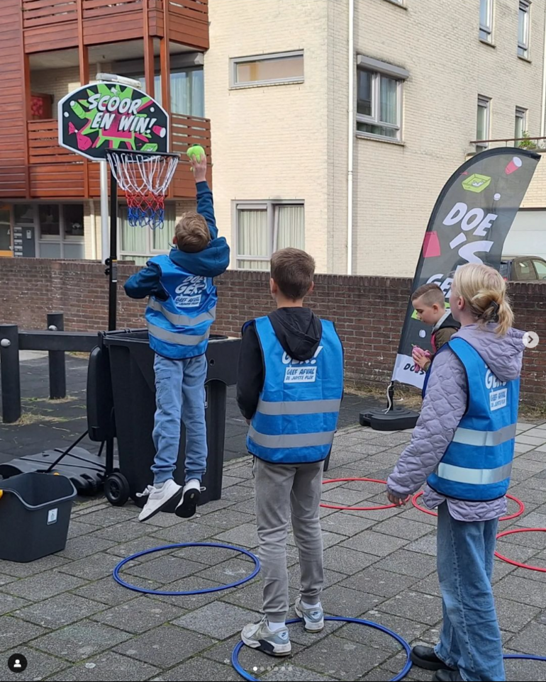 Kinderen die afval in basketbalnet gooien voor zwerfafvalspel